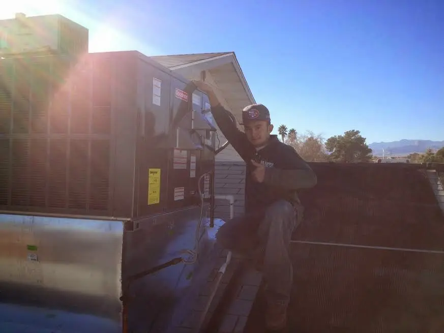 HVAC technician performing Heat Pump Repair on a rooftop unit in Wharton
