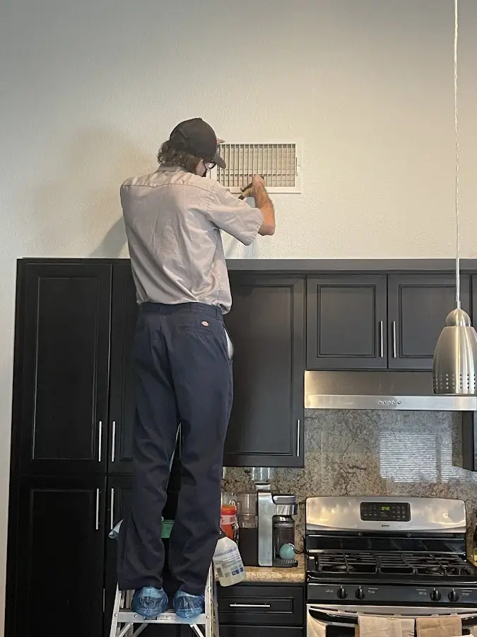 Technician inspecting an air vent during HVAC service in Wharton